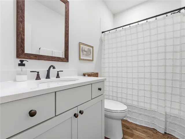 Gleaming stone counters and rich hardwood floors elevate this updated bathroom space.