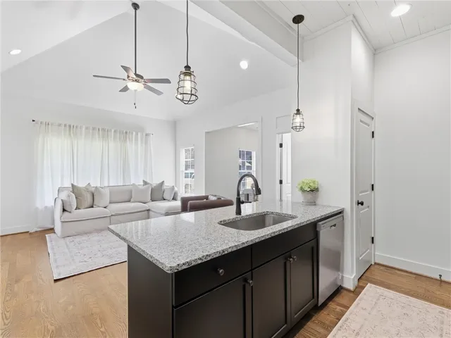 Granite counters and hardwood floors enrich this open-concept kitchen looking into the living space.