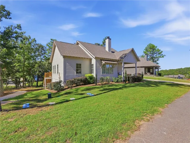 A grassy lawn leads up to this charming home featuring classic siding and shingle roofing.