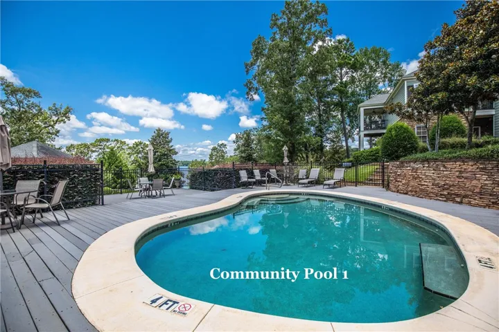 An inviting swimming pool is surrounded by spacious decking and mature trees.
