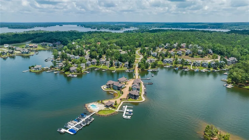 Aerial view showcasing a lush lakeside community surrounded by deep blue water and mature trees.