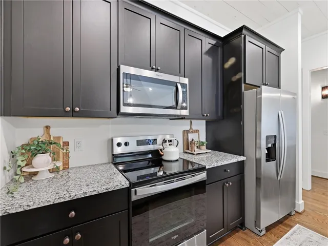 Striking dark cabinetry coordinates beautifully with speckled granite countertops and stainless steel appliances.