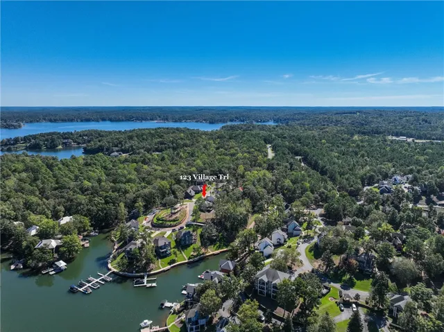 Lush forested hills surround a quiet waterfront community under vast blue skies.