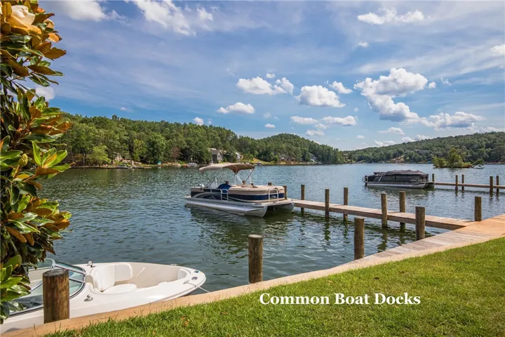 Wooden docks reach into calm waters under a bright sky with rolling green hills beyond.