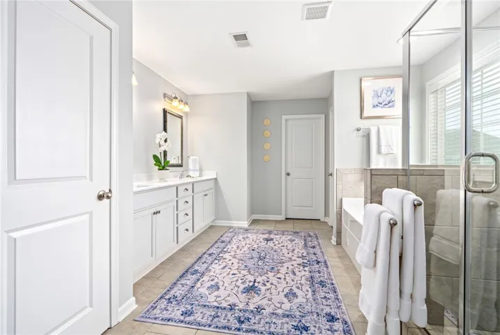 Tile flooring, stone counters, and a built-in soaking tub anchor this spacious layout.