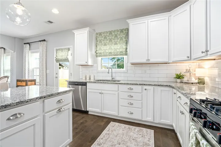 Gleaming stone countertops and classic cabinetry elevate this bright culinary space with rich hardwood flooring.