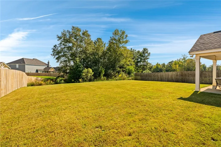 A spacious level lawn is fully enclosed by wood privacy fencing.