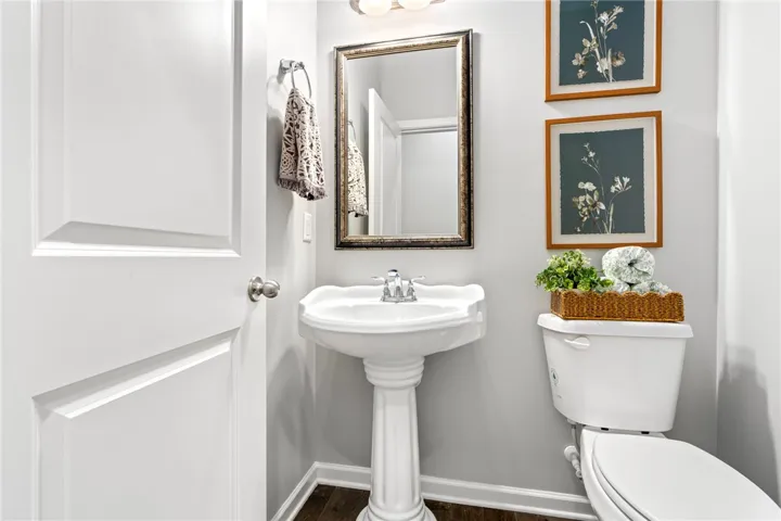 A classic pedestal sink pairs with rich wood flooring in this well-appointed powder room.