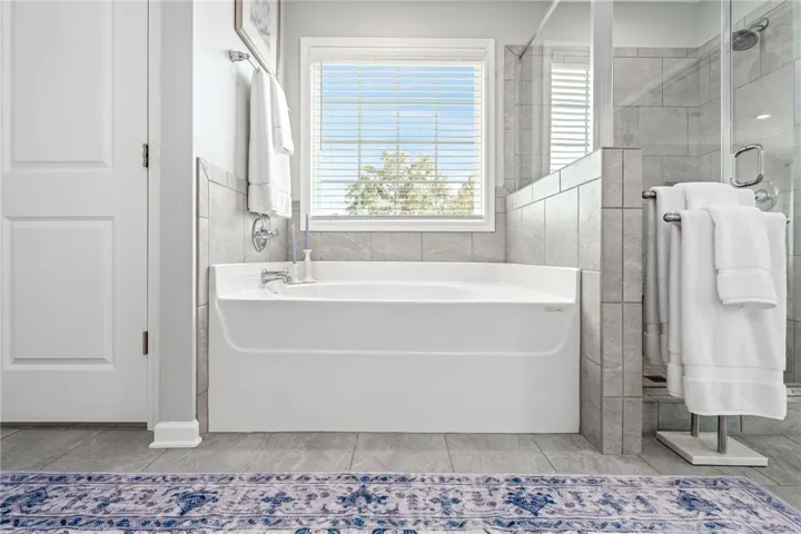 Tiled flooring and a deep soaking tub highlight this serene master bathroom space.