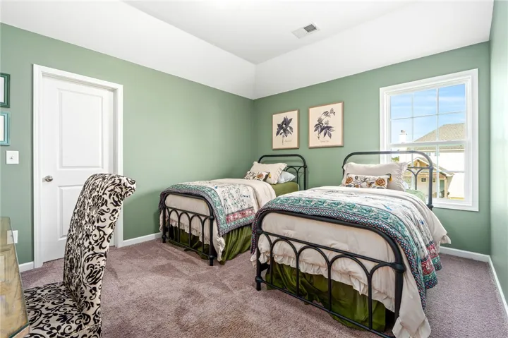 A spacious secondary bedroom features plush carpeting and a high tray ceiling.