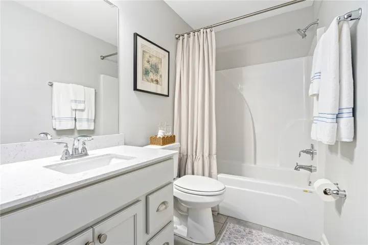 Smooth stone countertops and a modern tub shower create a clean, functional space.