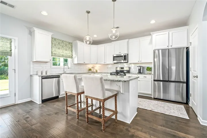 Rich hardwood floors contrast beautifully with classic white cabinetry and sleek granite countertops.