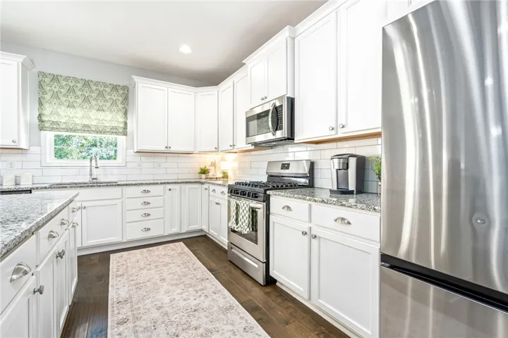 Rich hardwood flooring anchors this bright kitchen, complete with stone countertops and classic cabinetry.