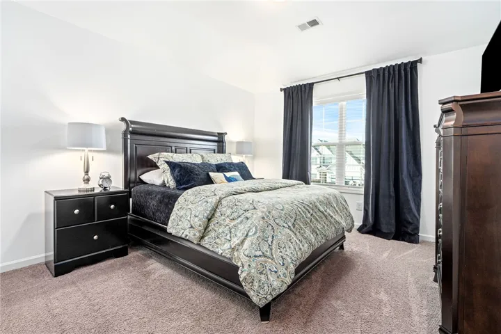 Plush carpeting and a vaulted ceiling elevate this airy, light-filled bedroom design.