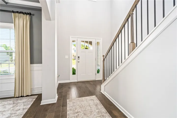 An inviting entrance foyer reveals rich hardwood floors and an elegant staircase leading upward.