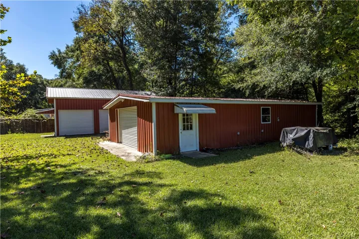 A spacious grassy yard surrounds multiple red metal outbuildings offering abundant storage options.