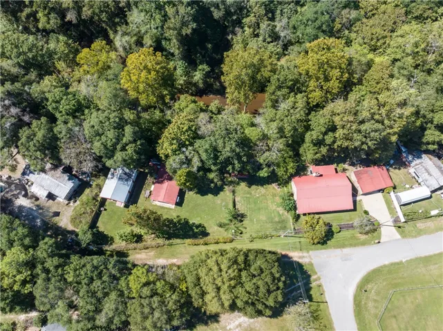 Mature trees surround this private riverside property featuring multiple outbuildings and green lawns.