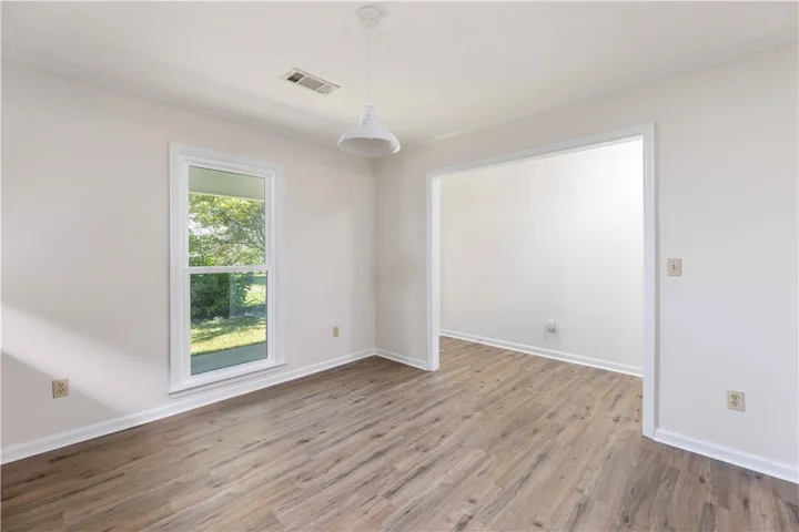 Gleaming wood floors anchor this open space leading seamlessly into an adjacent room.