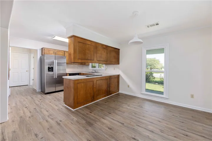 Rich wood cabinetry complements the wood-patterned flooring in this kitchen and dining area.