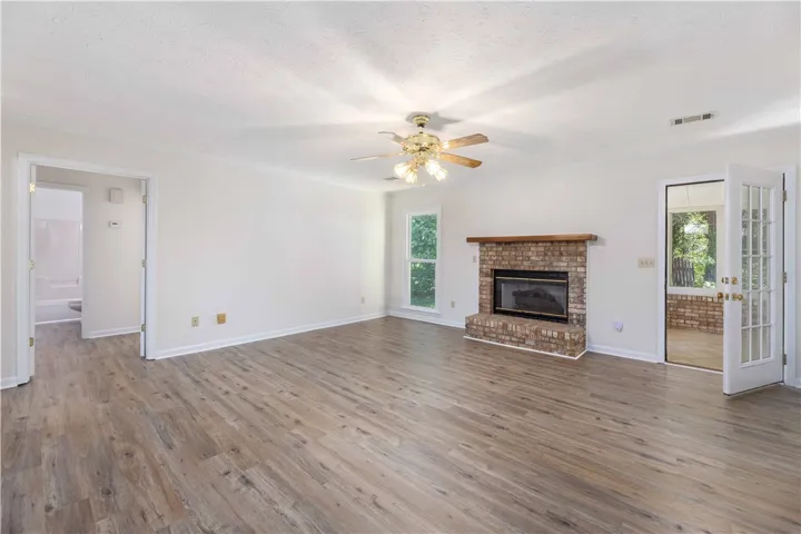 Rich wood-look flooring and a brick fireplace anchor this comfortable living area.