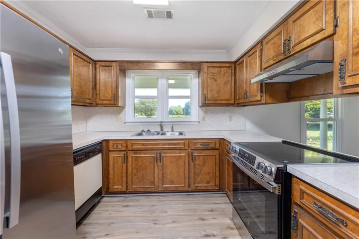 Rich wood cabinetry surrounds integrated appliances on durable wood-look flooring.