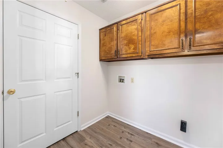 Rich wood cabinetry overhead complements durable plank flooring in this practical utility space.