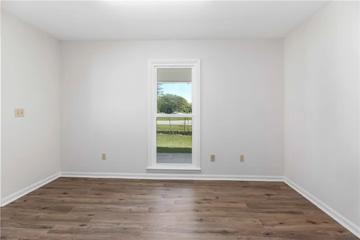 Rich wood-look flooring and crisp trim frame a tall window overlooking the yard.