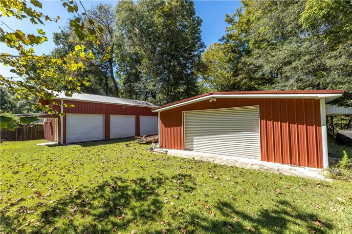 Generous metal outbuildings offer extensive storage and workspace options on a grassy lot.