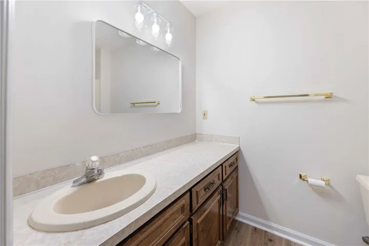 An integrated vanity countertop pairs with wood cabinetry in this functional restroom space.