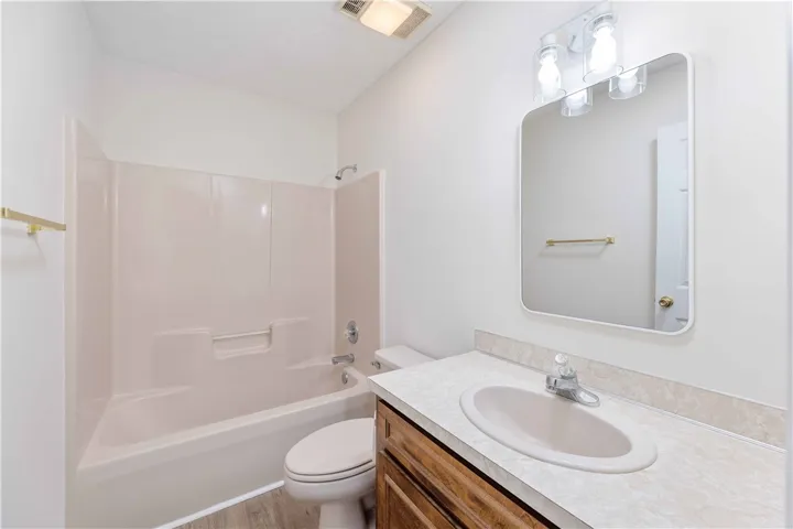 Functional bathroom design features a classic wood vanity and integrated tub and shower combination.