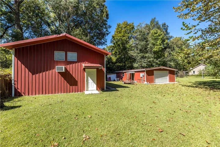 Detached metal outbuildings provide ample workshop space and storage on a grassy lawn.