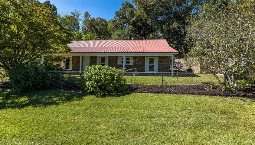 Mature trees frame a classic brick exterior topped by a durable metal roof.