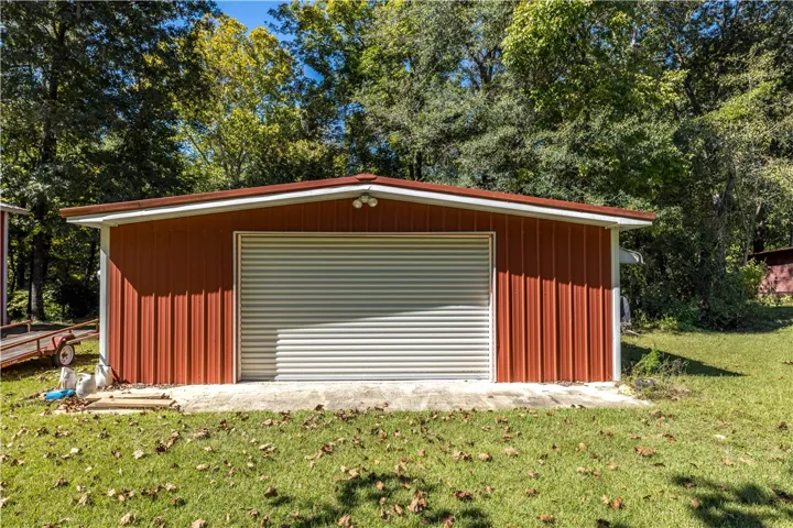 A spacious detached metal outbuilding provides excellent storage options set against a mature wooded backdrop.