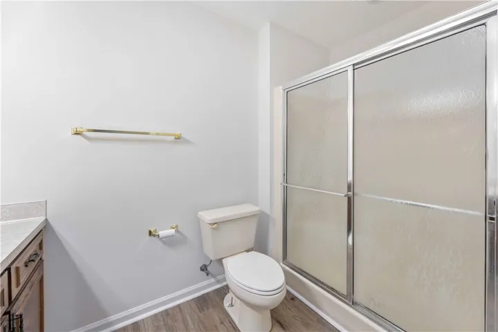 Functional layout features a sliding glass shower door and durable wood-look flooring.