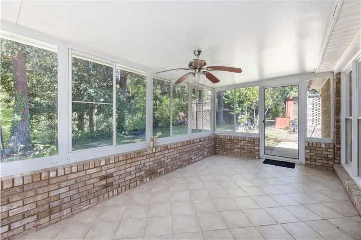 Sunlight streams through expansive windows in this tiled sunroom lined with classic brick accents.