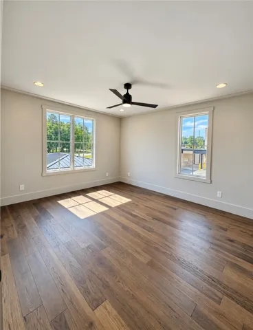 Rich hardwood floors and classic wood-framed windows define this spacious secondary bedroom.