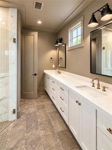 A long dual vanity and stone tile flooring define this beautifully detailed space.