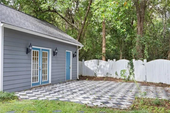 A patterned patio and French doors frame this versatile detached backyard structure.