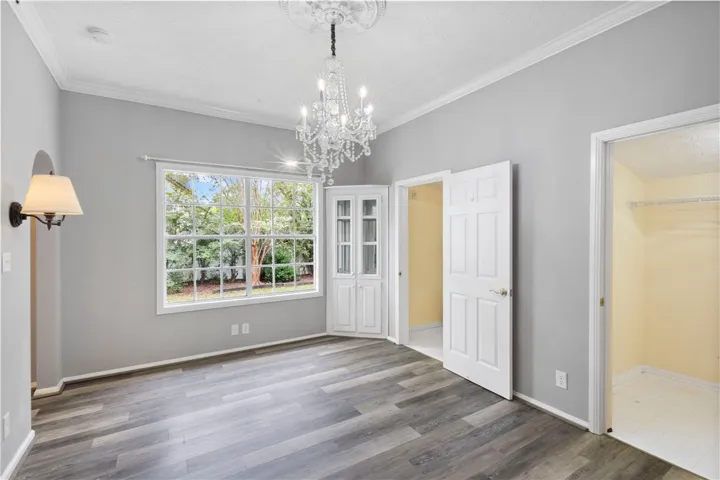 Elegant crown molding and classic wood-look flooring anchor this versatile light-filled room.