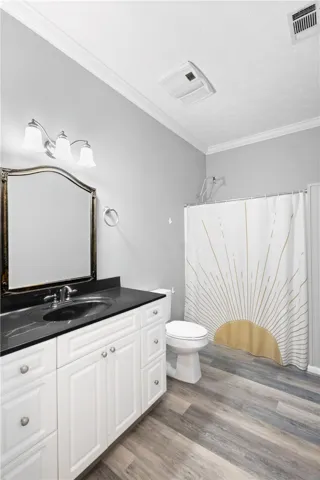 Crown molding highlights the ceiling of this bathroom containing a dark countertop vanity.