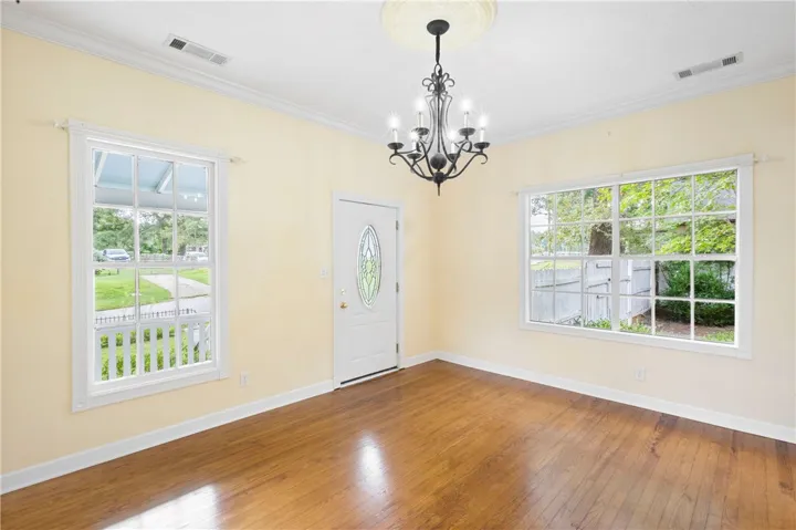 Rich hardwood floors and classic crown molding frame this inviting entryway filled with natural light.