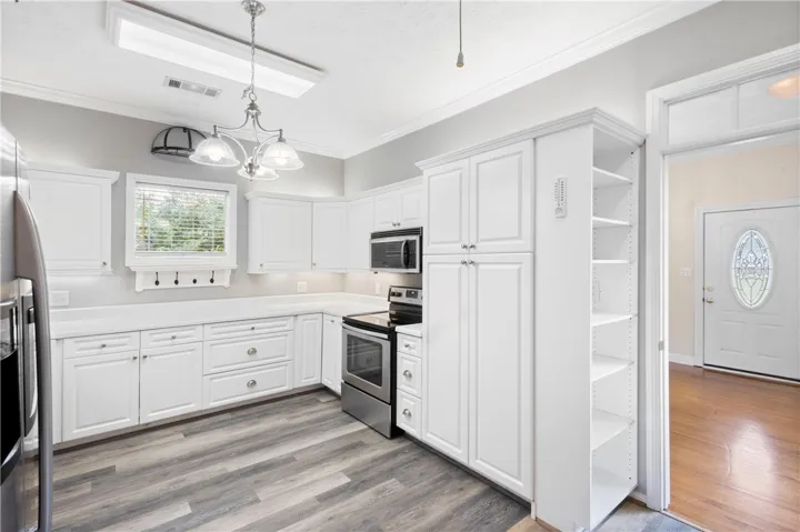 Bright white cabinetry and modern countertops pair beautifully with contemporary flooring in this functional space.