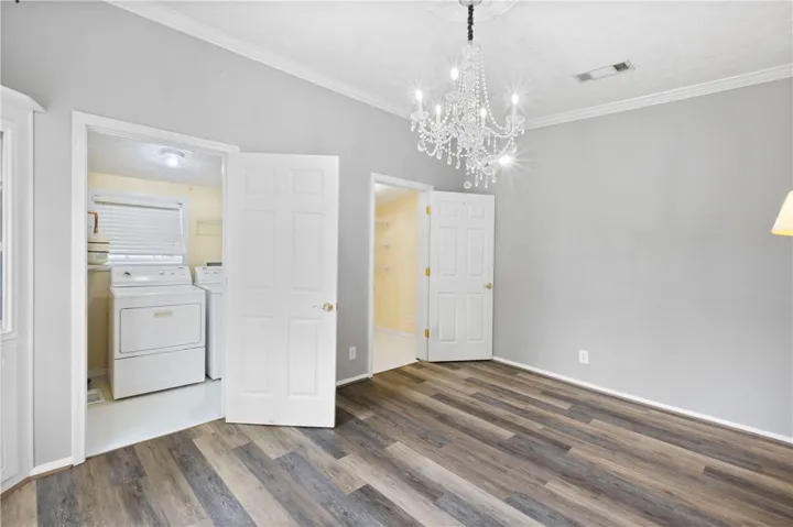 Elegant wood-look flooring and a classic crystal chandelier elevate this versatile living space.