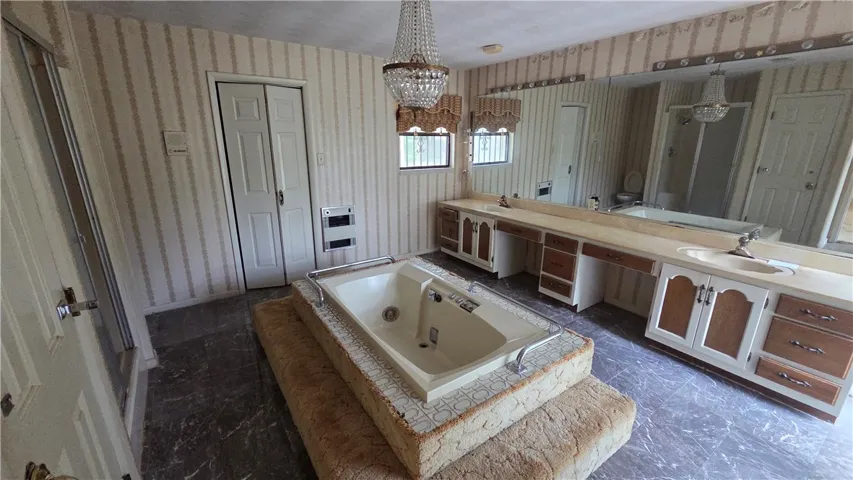 A spacious bathroom features a sunken soaking tub and a long vanity area with dual sinks.