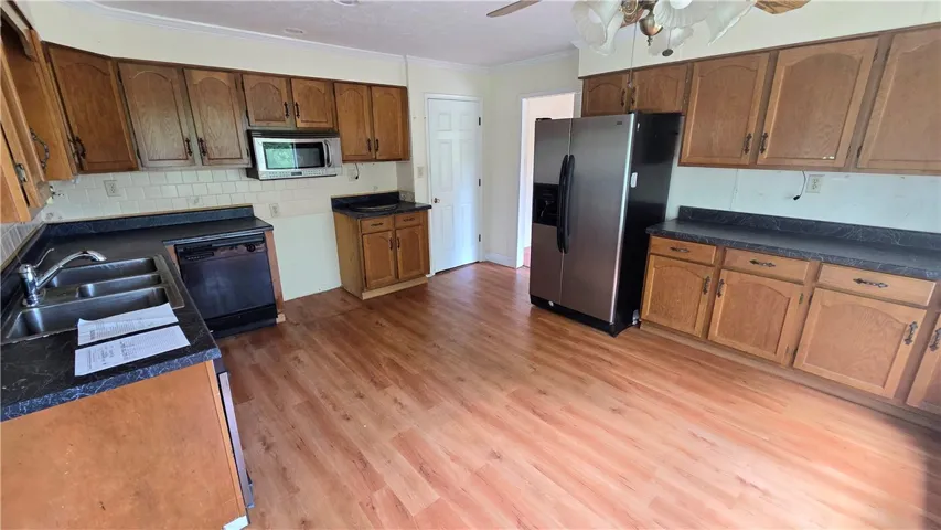 A spacious kitchen layout features ample wood cabinetry paired with warm wood-look flooring.