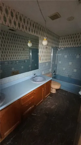 Retro charm defines this vintage bathroom with detailed wallpaper and a tiled tub surround.