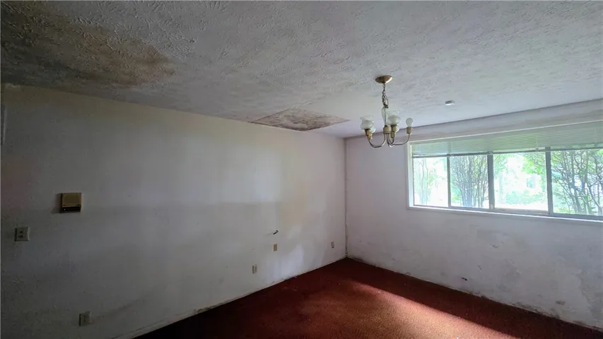 A spacious room offers potential for customization with classic textured ceilings and a large window.
