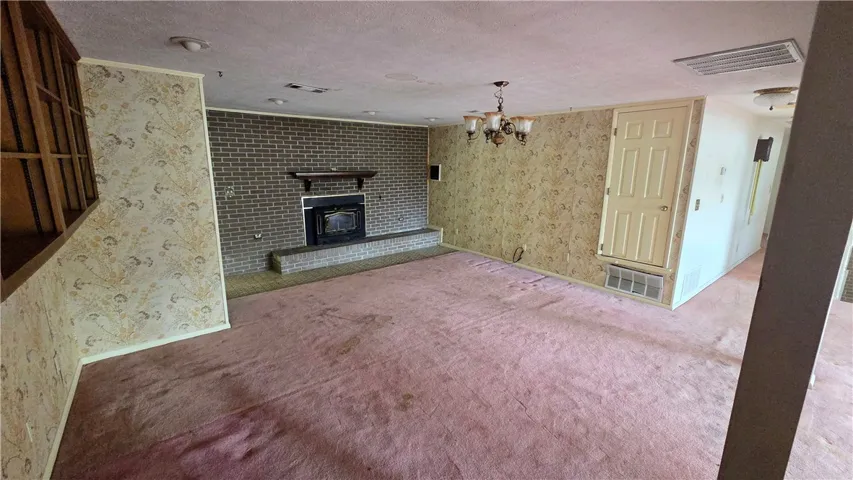 A classic brick fireplace anchors this spacious living area featuring patterned wall coverings.