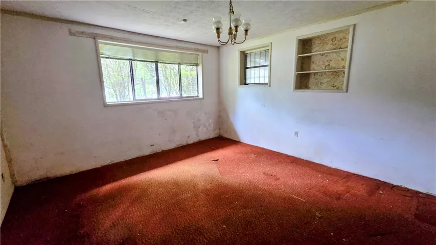 Natural light streams through multiple windows highlighting built-in wall shelving and carpeted floors.