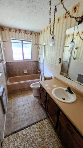 A spacious bathroom layout features tile flooring and a built-in tub under a window.